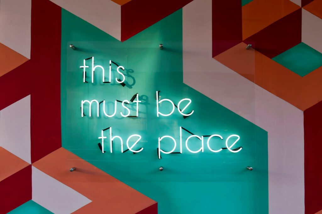 A colorful wall with a neon sign saying "This must be the place"